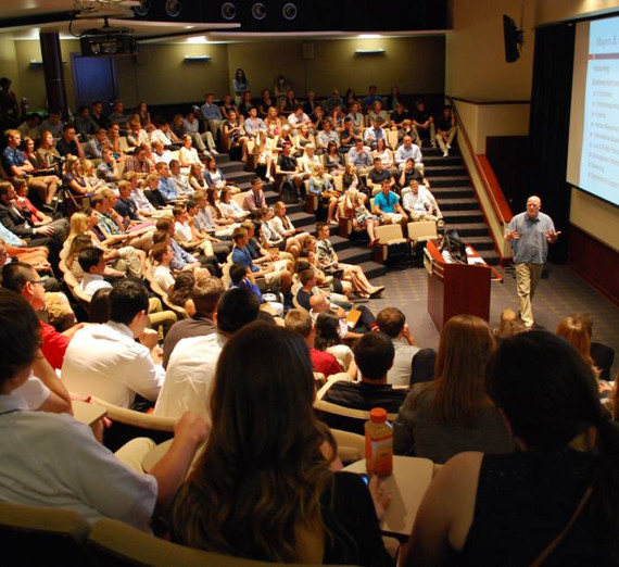 Женщина в выпускной шапочке и мантии поднимает диплом и улыбается